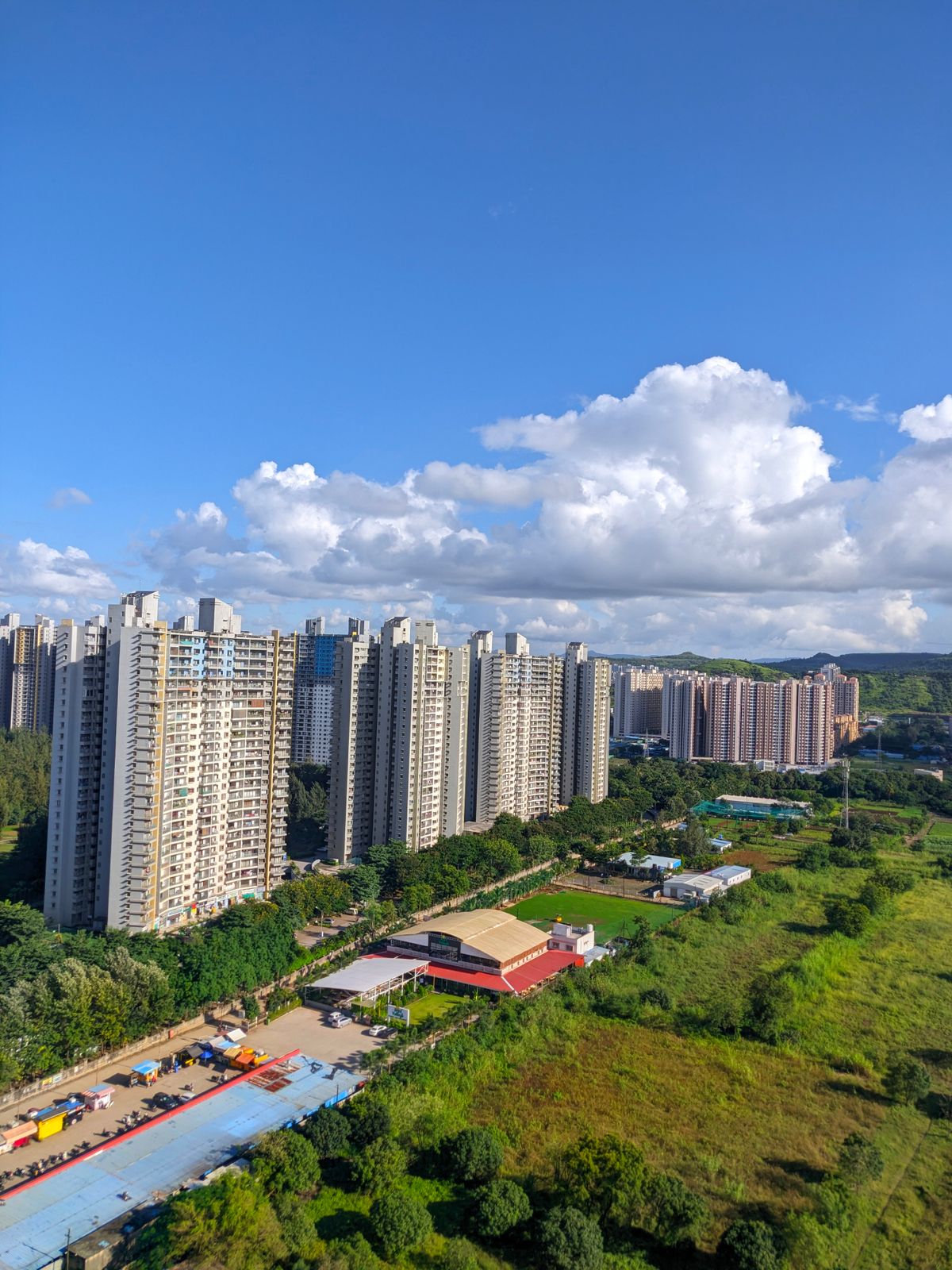 Tall residential towers beside open green land in Pune