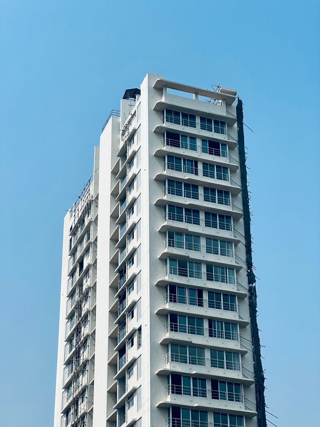 White high-rise residential tower against a clear blue sky