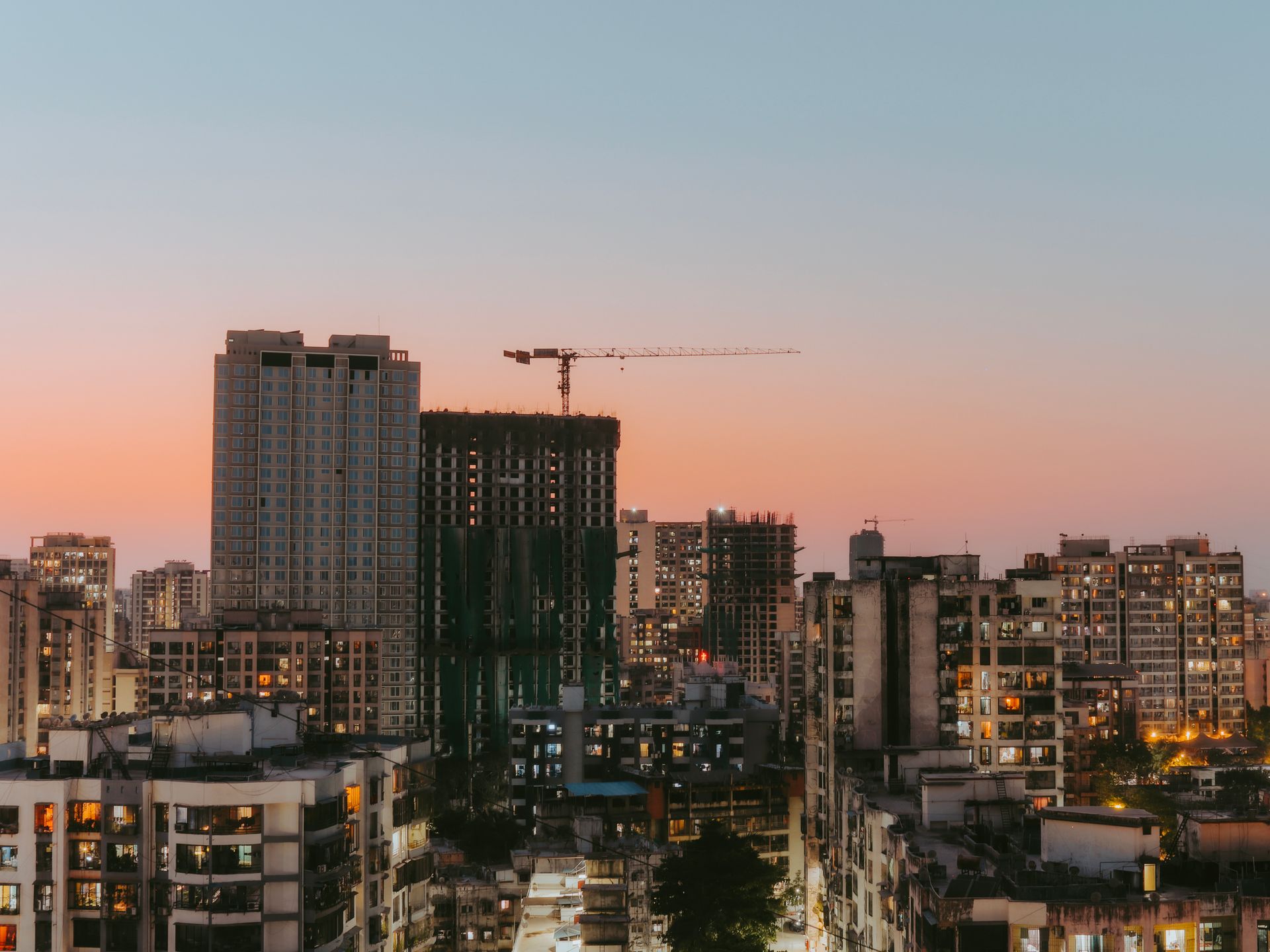 City skyline at dusk with high-rise towers and a construction crane